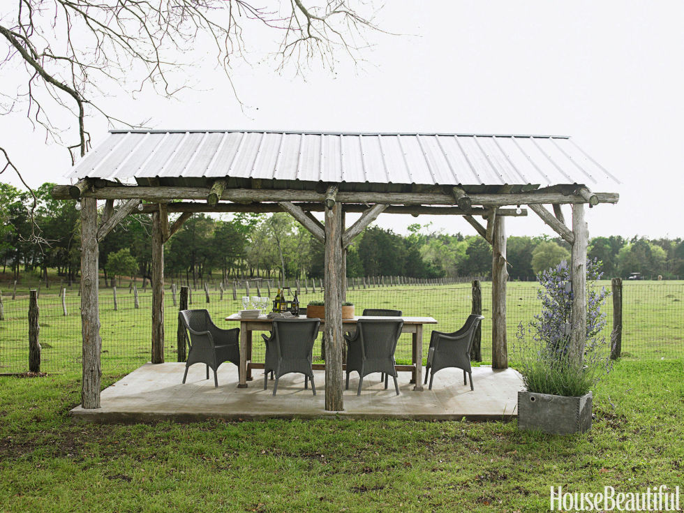 A rustic gazebo is the farm's only real dining room. Janus et Cie's indoor-outdoor Cannes wicker chairs surround an antique pine table that Barber stained gray to blend with the weathered posts.