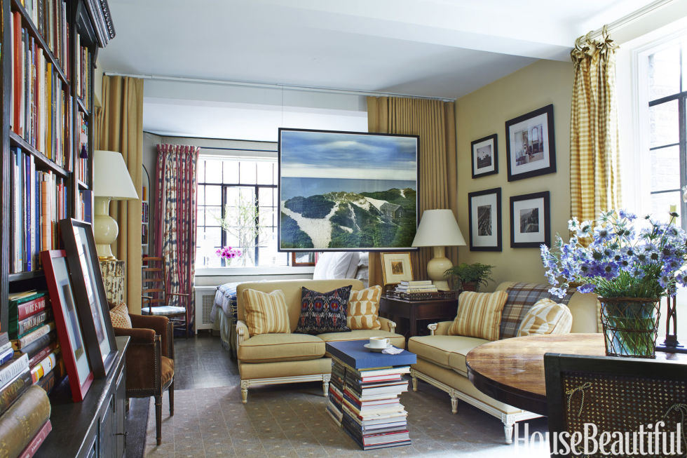 The linen used for room-divider curtains and custom love seats, Claremont's Serge Antique, matches the paint on the living-area walls, Benjamin Moore's Rich Cream. The Romano lamps, by Christopher Spitzmiller, give a cozy feel to the room. Ceiling-mounted wires suspend the large Read McKendree photograph while the Tilda rug, by Patterson Flynn Martin, bring the numerous looks altogether.