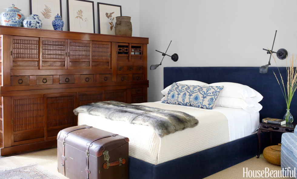 In a Sonoma house decorated by Rela Gleason, the master bedroom was designed around the antique mizuya chest, with its bold iron hardware. A vintage "boot" trunk from an old English automobile stands at the foot of a contemporary bed upholstered in indigo chenille. Bed linens by Garnet Hill. Wall lights by Restoration Hardware.